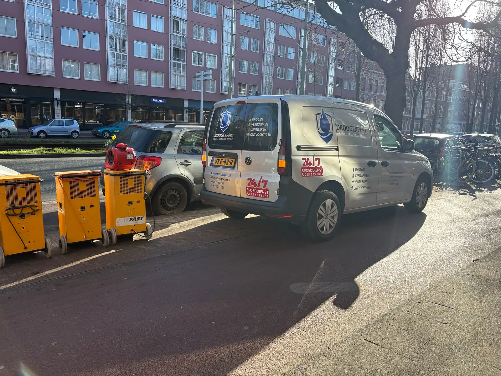 Droogexpert-servicewagens met gele bouwdrogers op locatie in Amsterdam